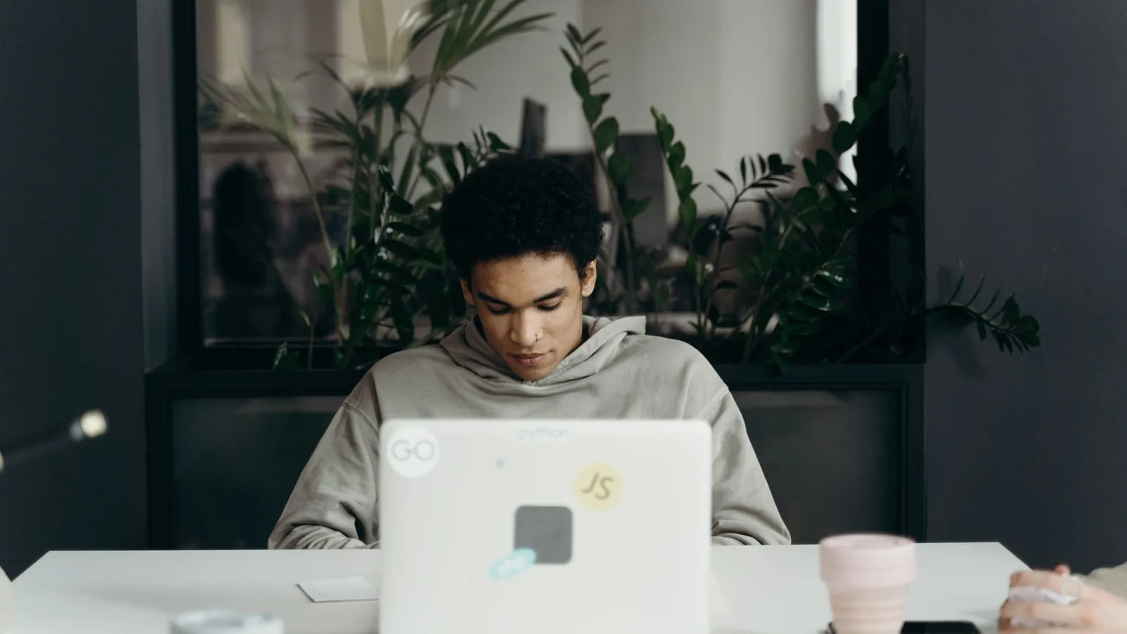 Focused young professional working on a laptop in a modern office environment.