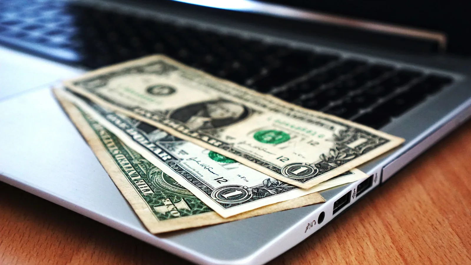 Close-up of US dollar bills placed on a laptop symbolizing digital finance and economy.