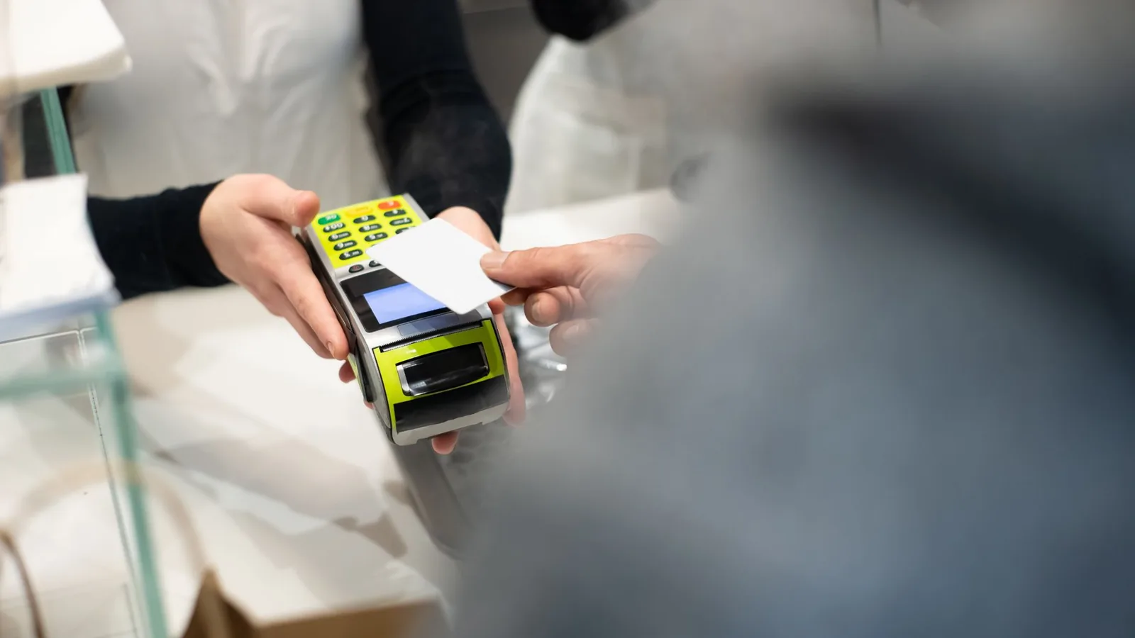 A customer pays with a card at a payment terminal in a modern retail store.