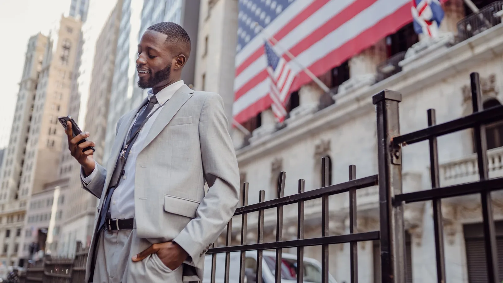 African American businessman smiling while checking his phone on a city street in New York.