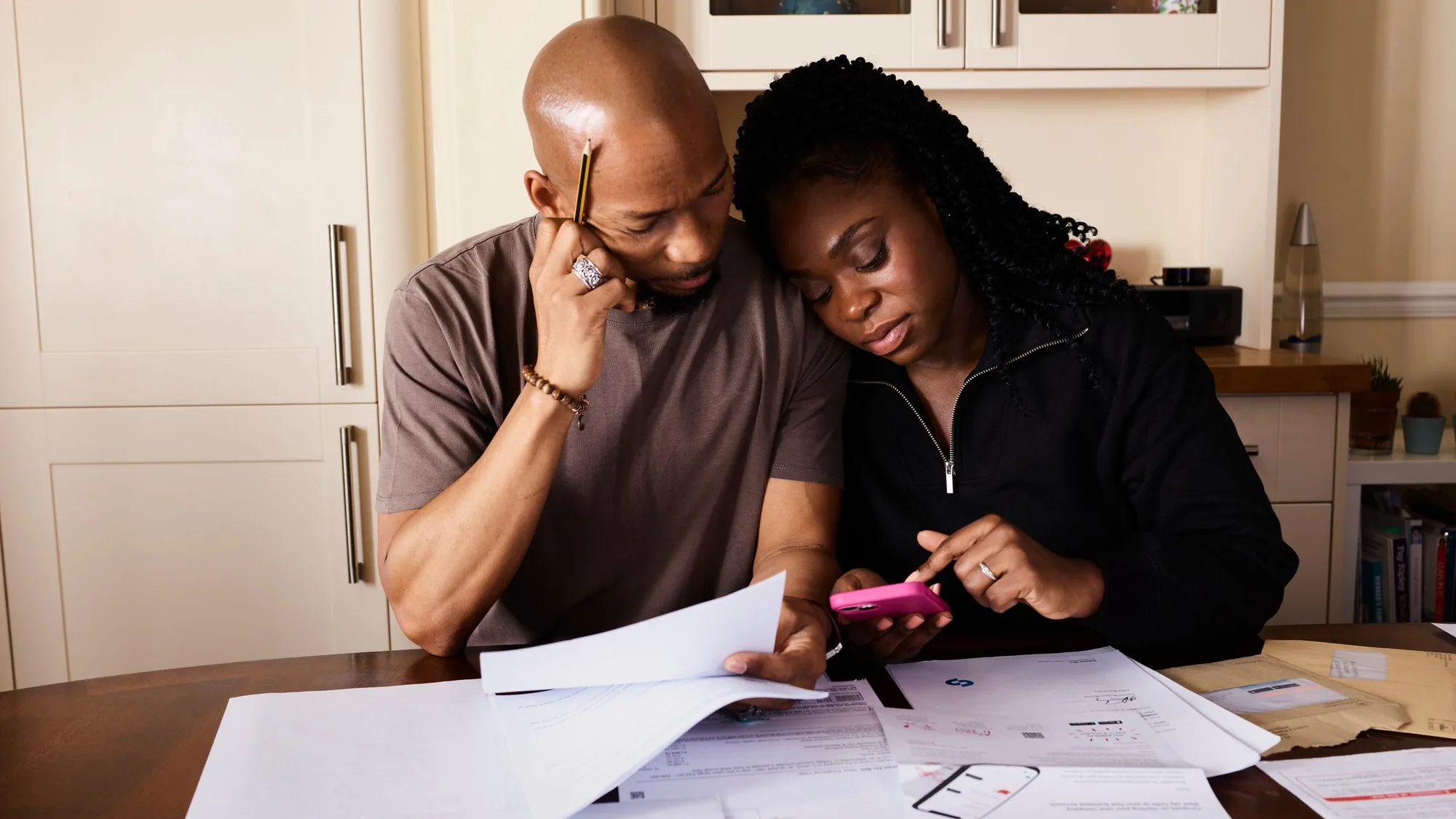 A couple at their kitchen table going through household bills and paperwork