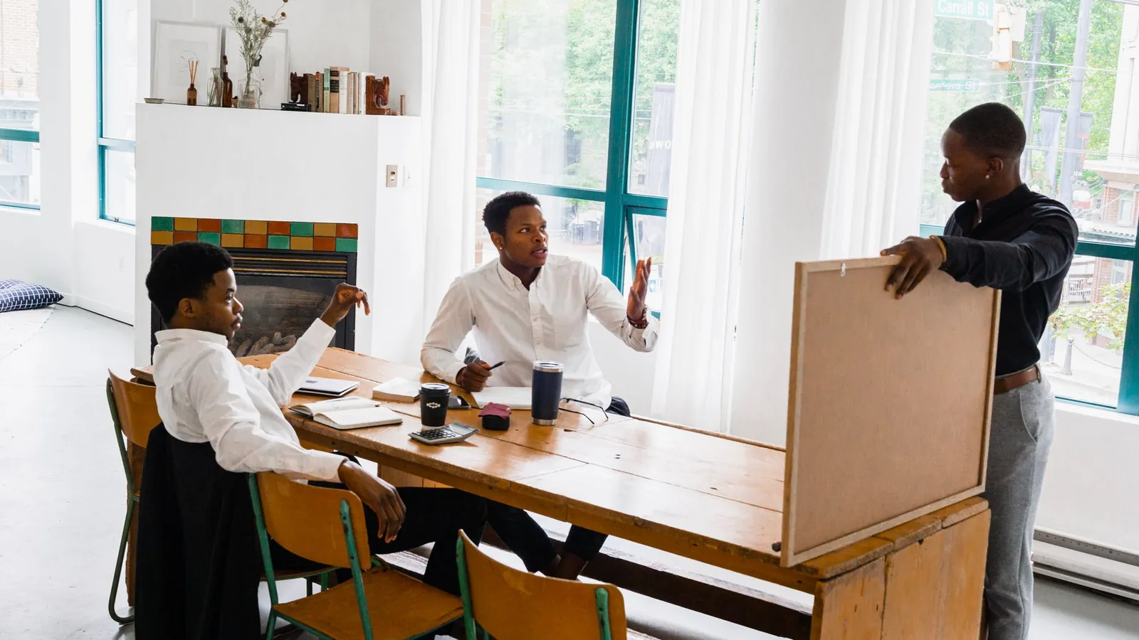 Three men discussing a project at a table in a bright office setting.