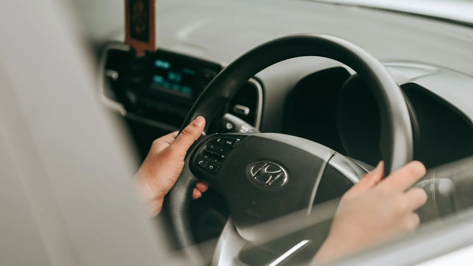 Close-up view of hands holding the steering wheel inside a car.
