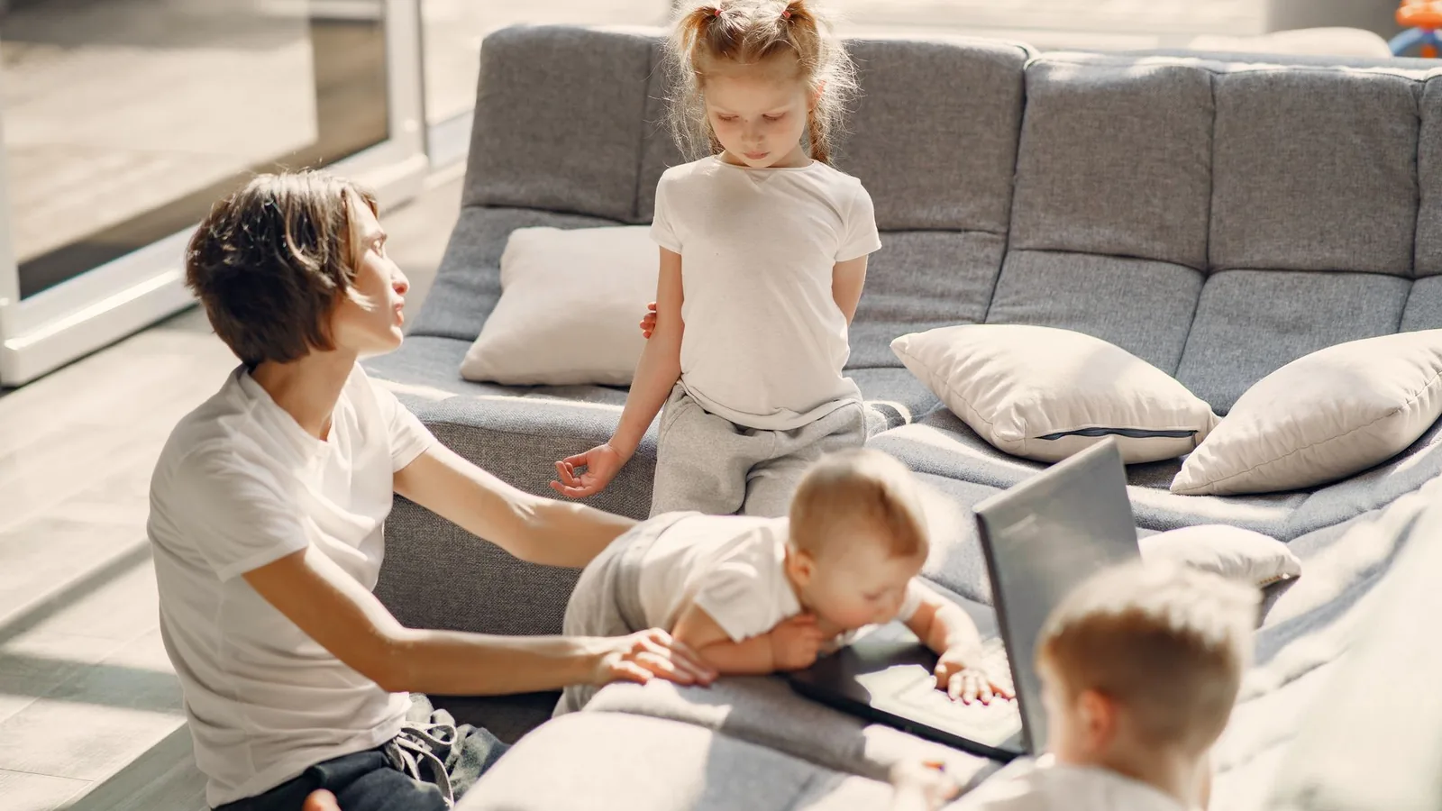 Mom and kids enjoying quality time in sunlit living room, highlighting family togetherness.