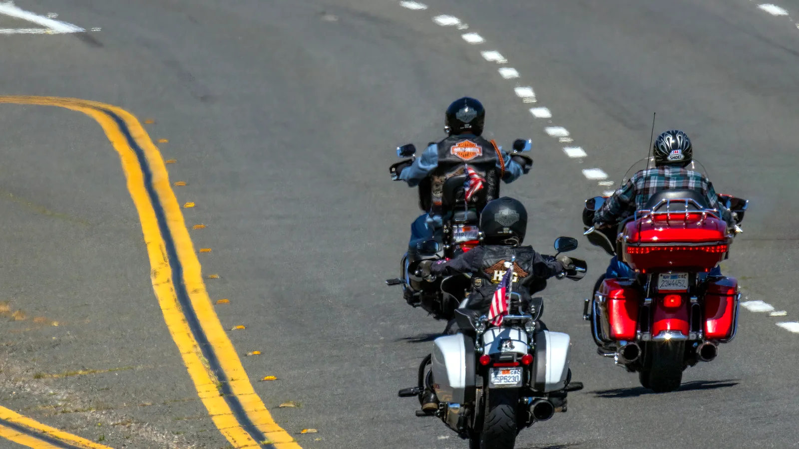Three motorcyclists riding freely on a highway, enjoying the thrill of the open road.