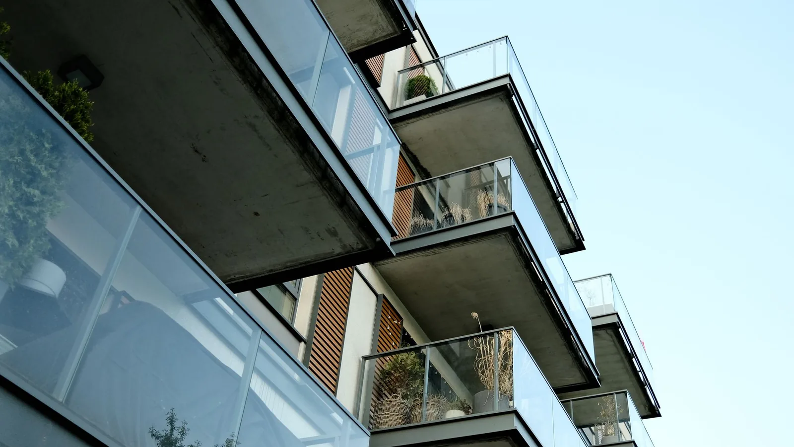A modern residential building's glass balconies under a clear sky, showcasing contemporary architecture.