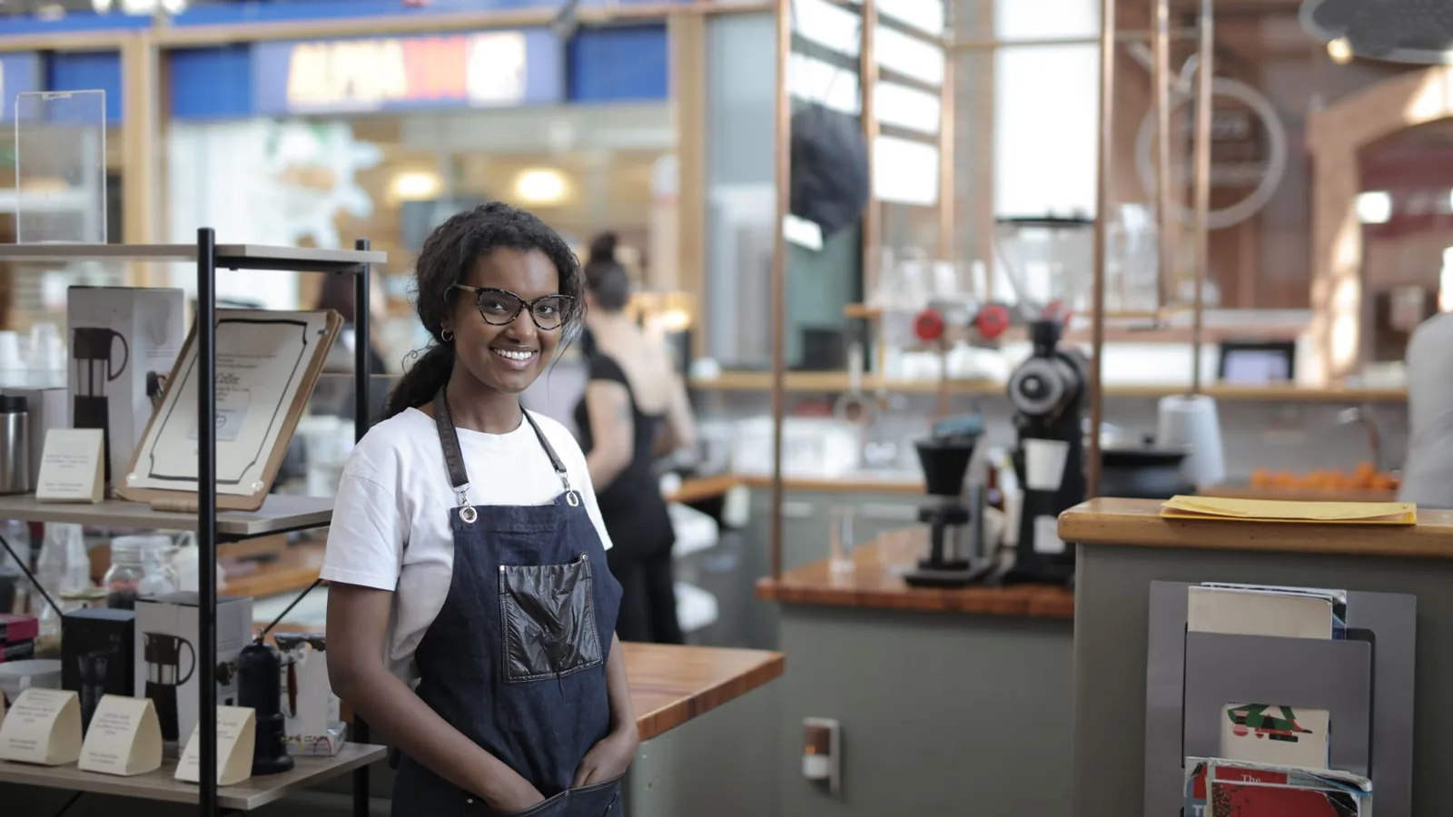 Smiling barista standing in a stylish café, showcasing entrepreneurial spirit.