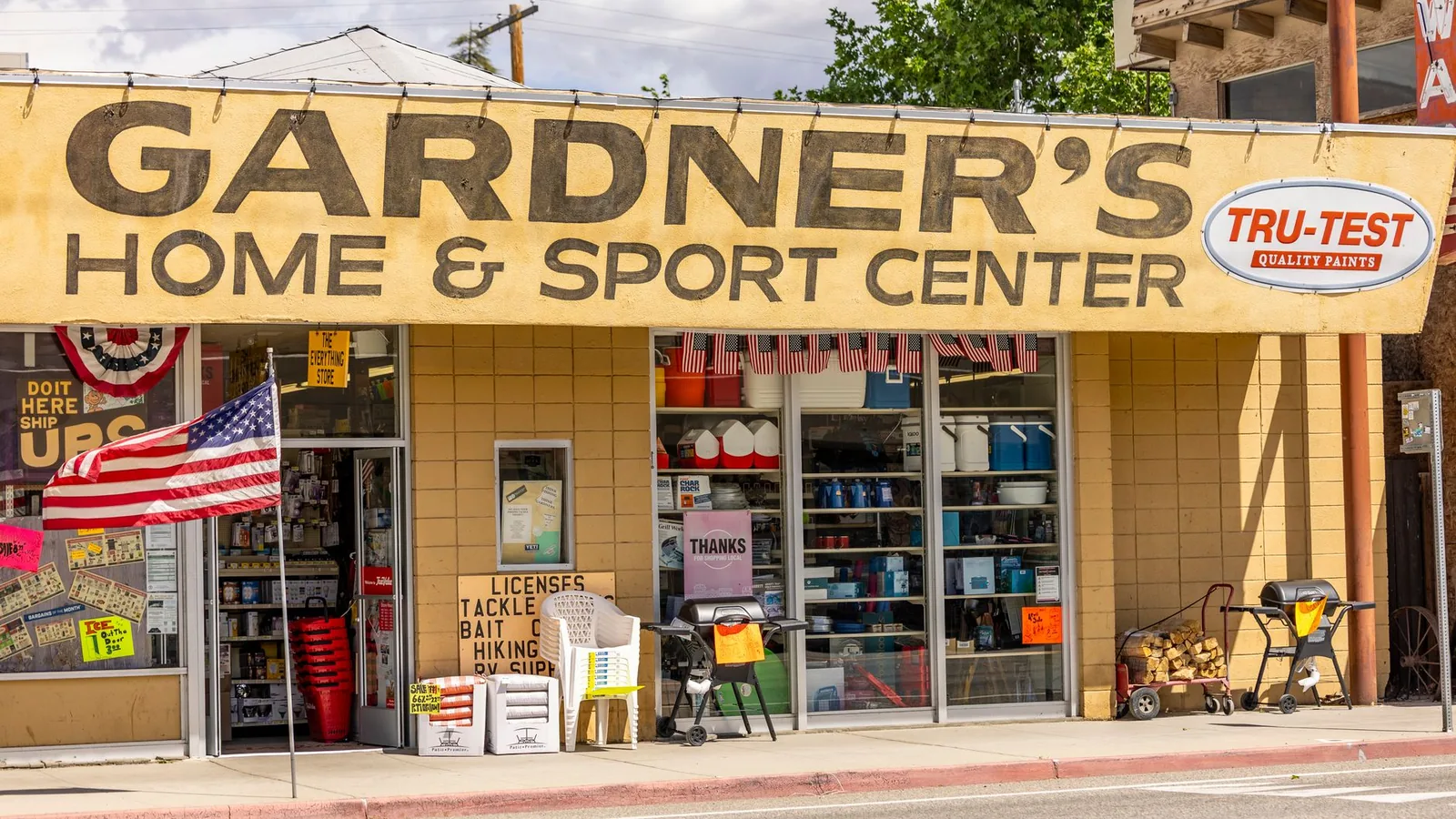 Front view of Gardner's Home & Sport Center with American flag and outdoor displays.