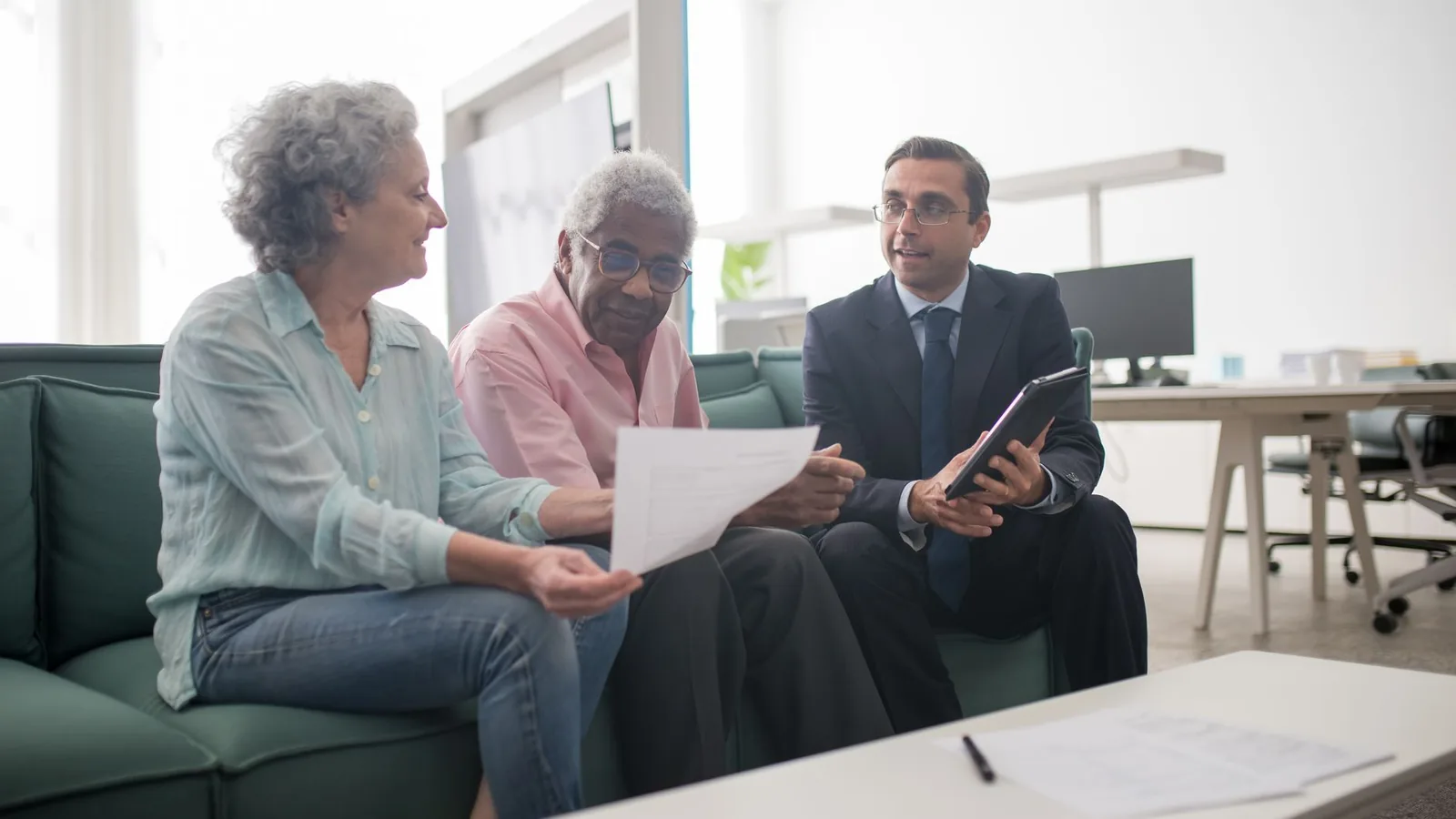 Senior couple discussing documents with a business advisor in a modern office setting.