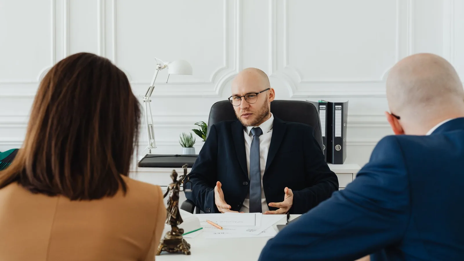A professional business meeting with a lawyer and clients in a modern office setting.