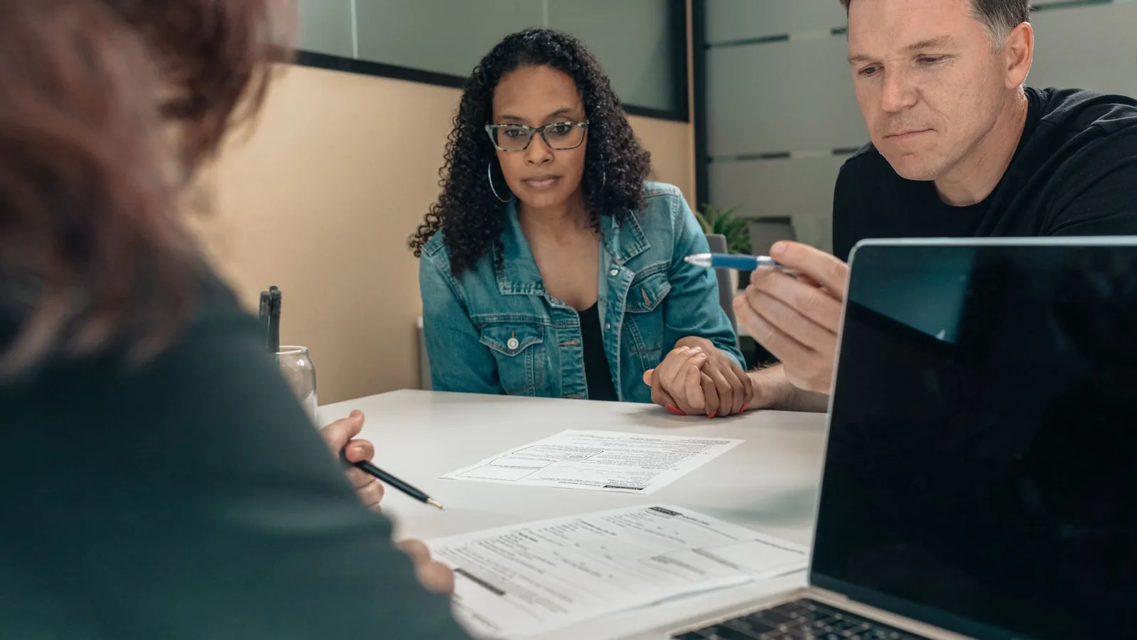 A couple reviewing documents with a professional in an office setting, focusing on financial planning.