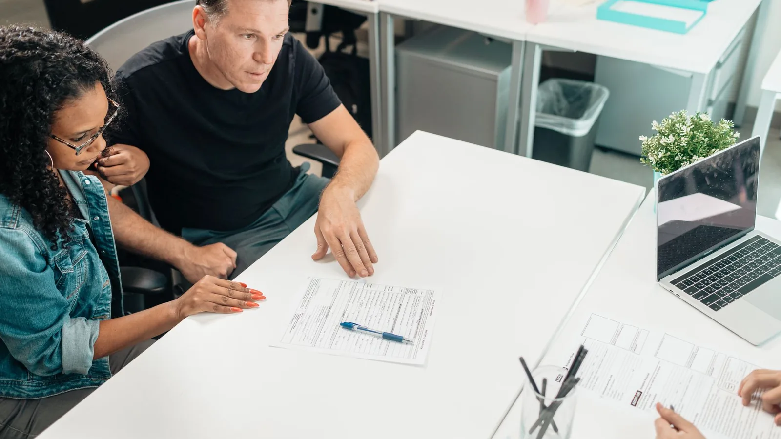 A couple discusses legal documents with a professional in a modern office setting.